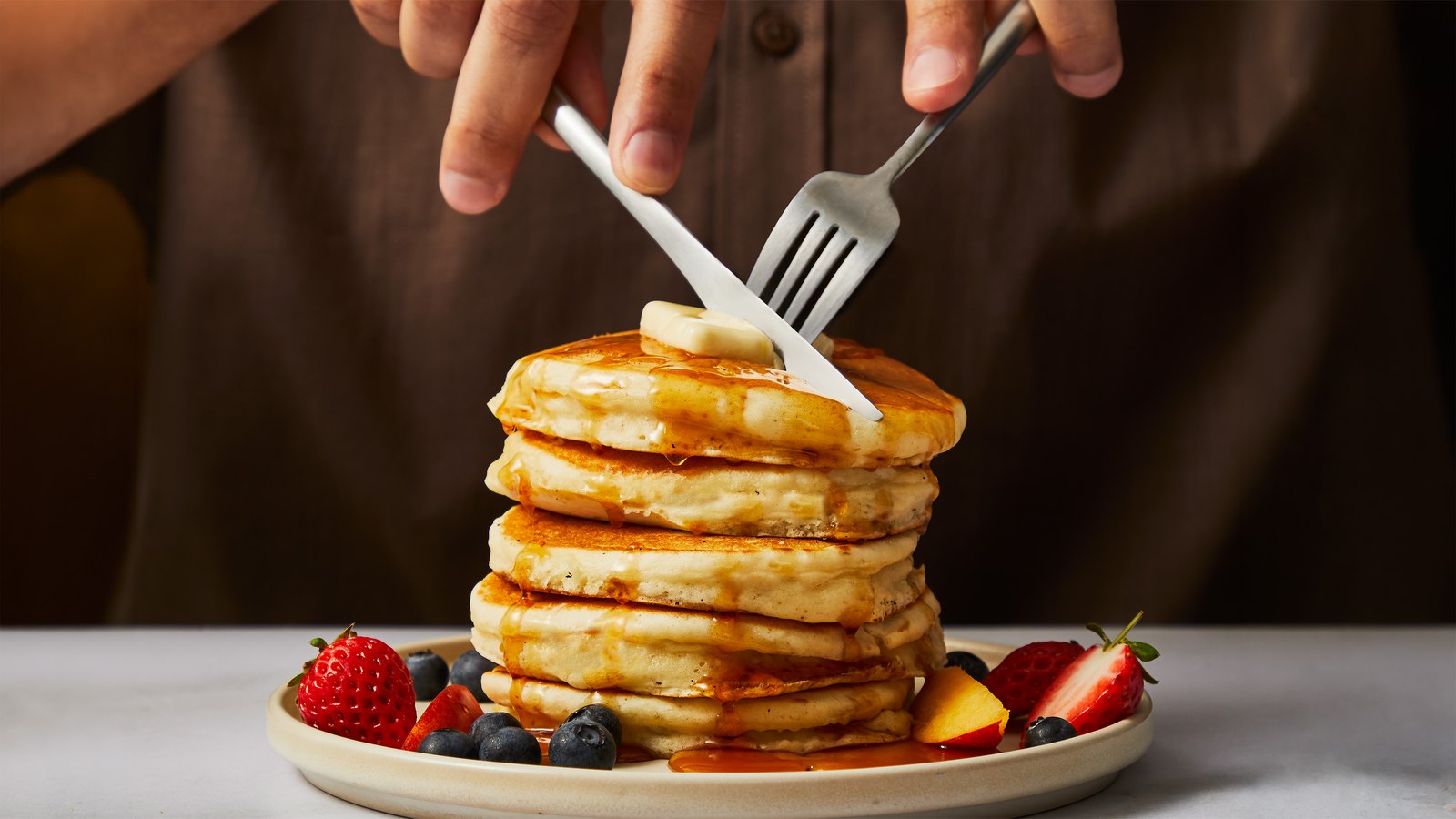 A stack of Factor pancakes with berries and syrup