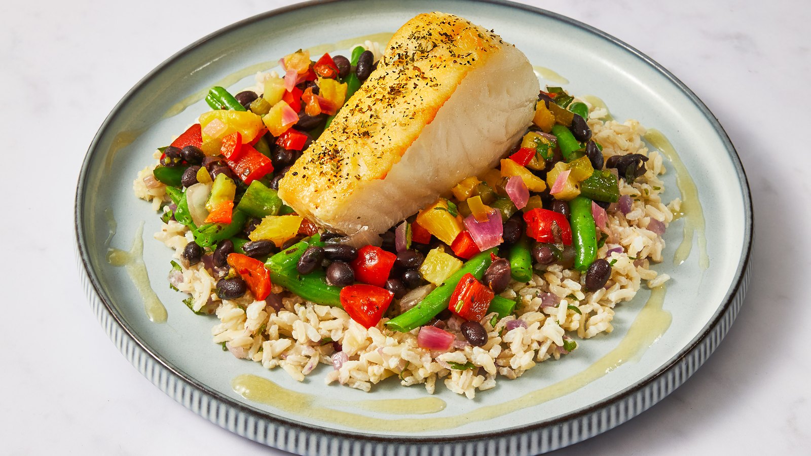 A Factor cod fillet over brown rice with black beans and peppers