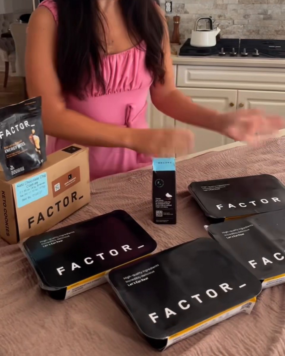 Sealed Factor meal trays laid out on the table as Kristel unpacks the box